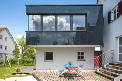 Haus mit rechteckigem Anbau und schwarzer Glasfassade
