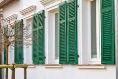 Jahrhundertwende-Haus mit weißer Fassade und grünen Lamellen-Fensterläden.